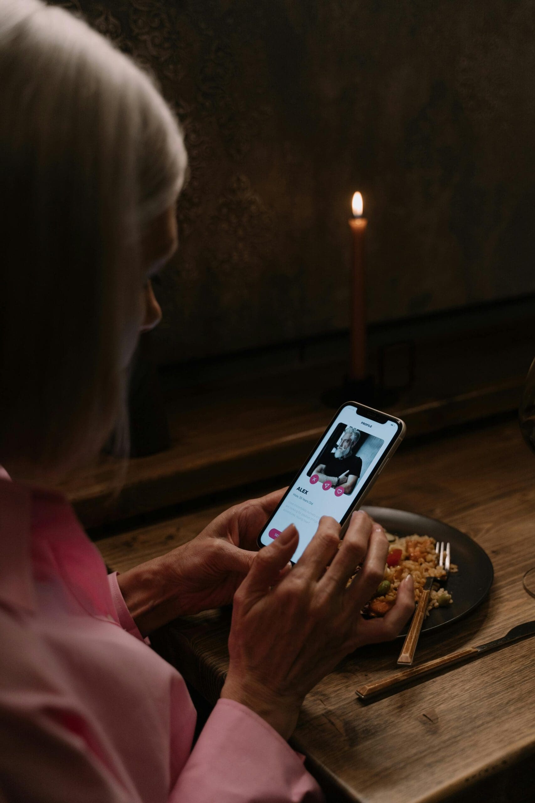 Woman using dating app on smartphone during dinner, representing online dating behavior and emotional investment