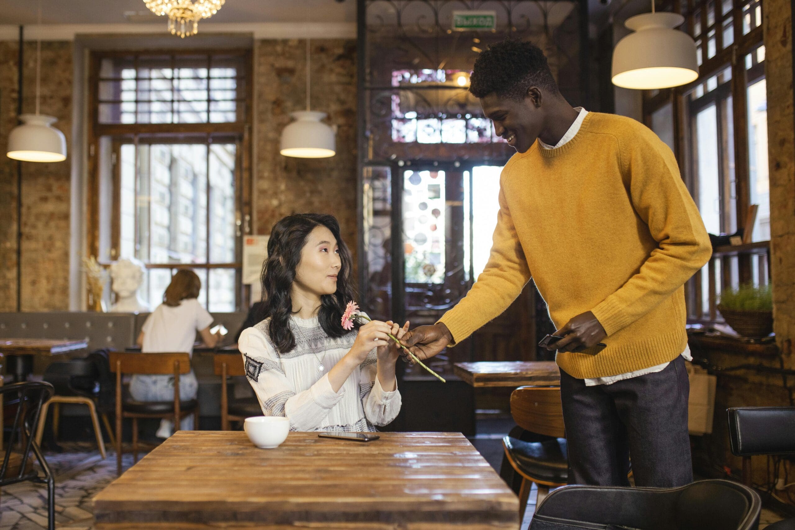 Man giving woman a flower on a first date at café, representing early attachment and emotional pacing
